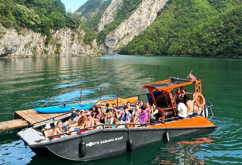 Group camping along Berisha River, Albania – Boat trip, crystal-clear waters, mountains, and nature.
