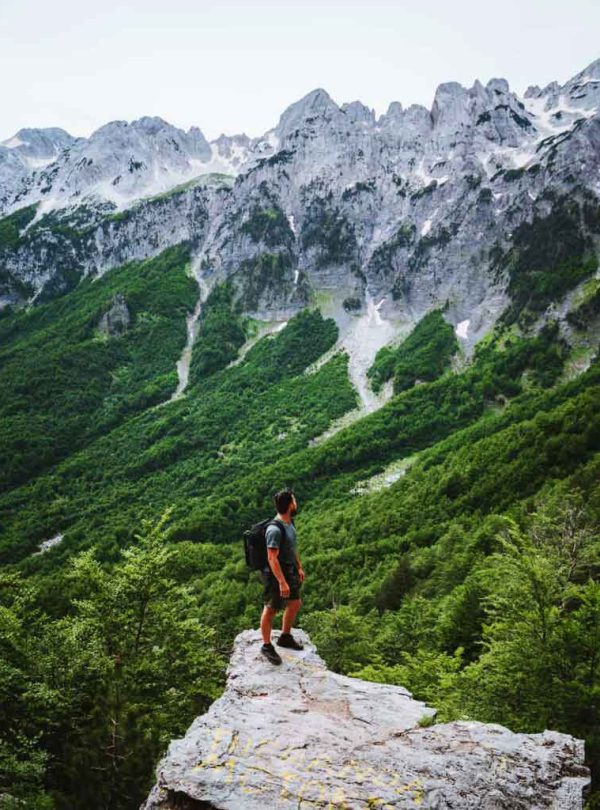 Hiker trekking through the stunning mountains of Albania, with scenic views of Valbona Valley and Theth.