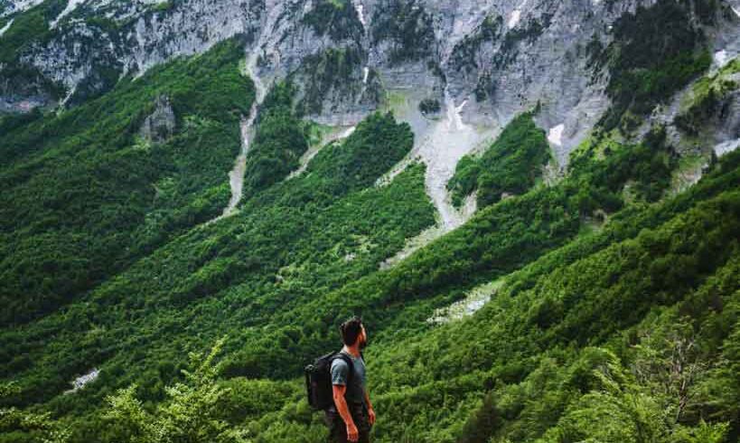 Hiker trekking through the stunning mountains of Albania, with scenic views of Valbona Valley and Theth.