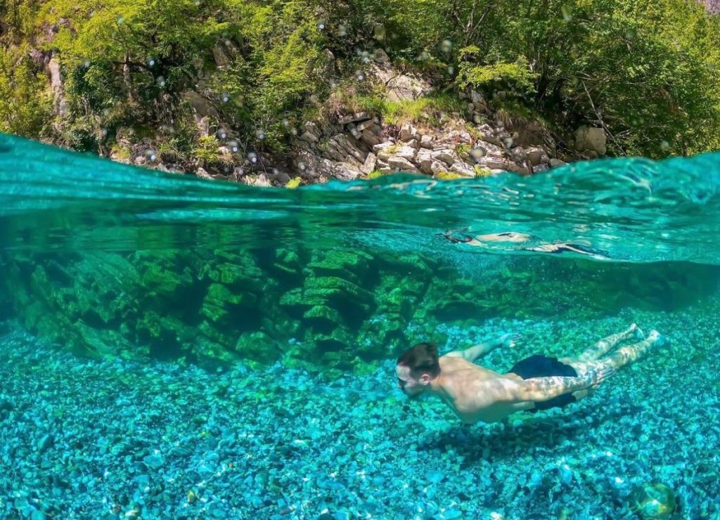 A stunning view of Shala River in Albania, with clear blue water surrounded by green mountains.