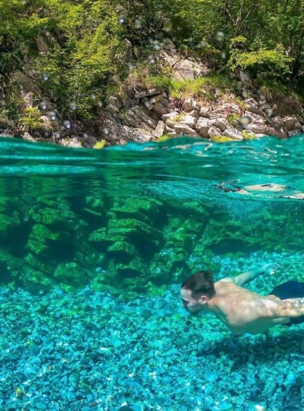 A stunning view of Shala River in Albania, with clear blue water surrounded by green mountains.