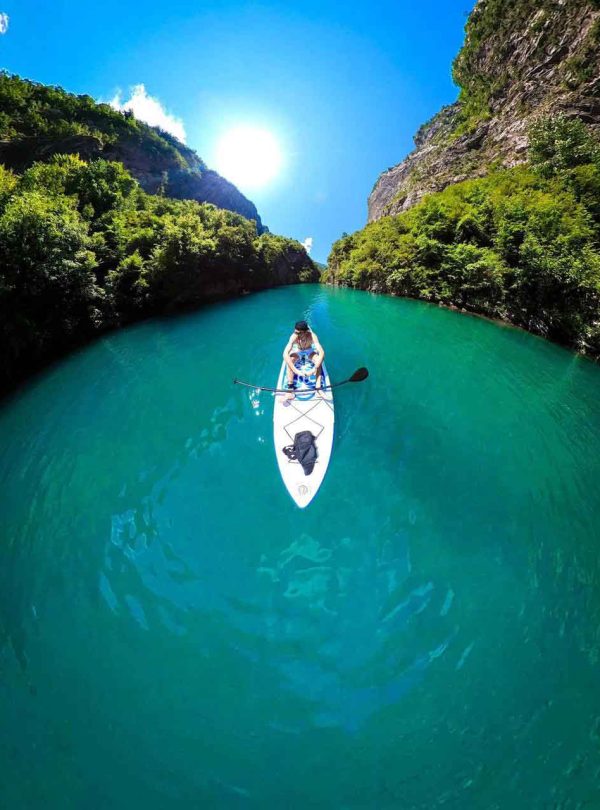 Rafting adventure on a river in Albania, with clear water and surrounded by mountains.