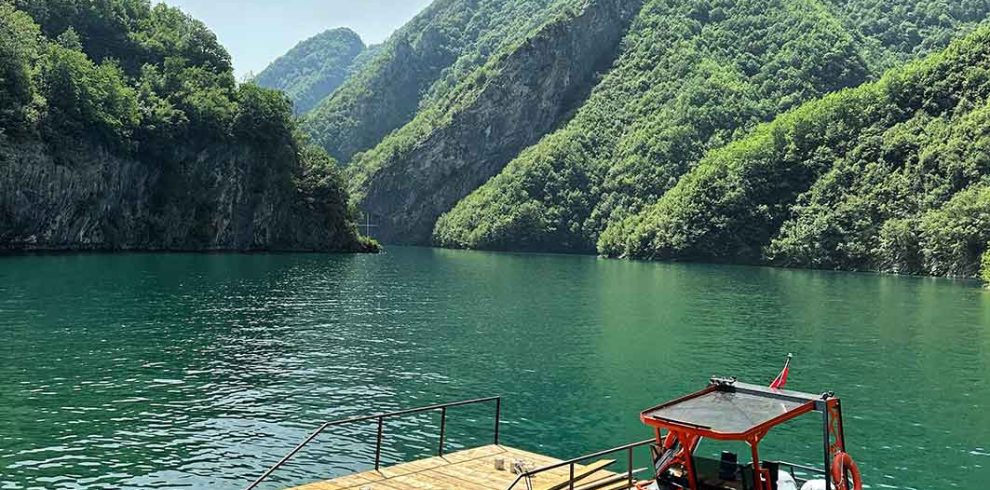 A beautiful boat on clear water, surrounded by mountains in Albania, offering a scenic tour experience.